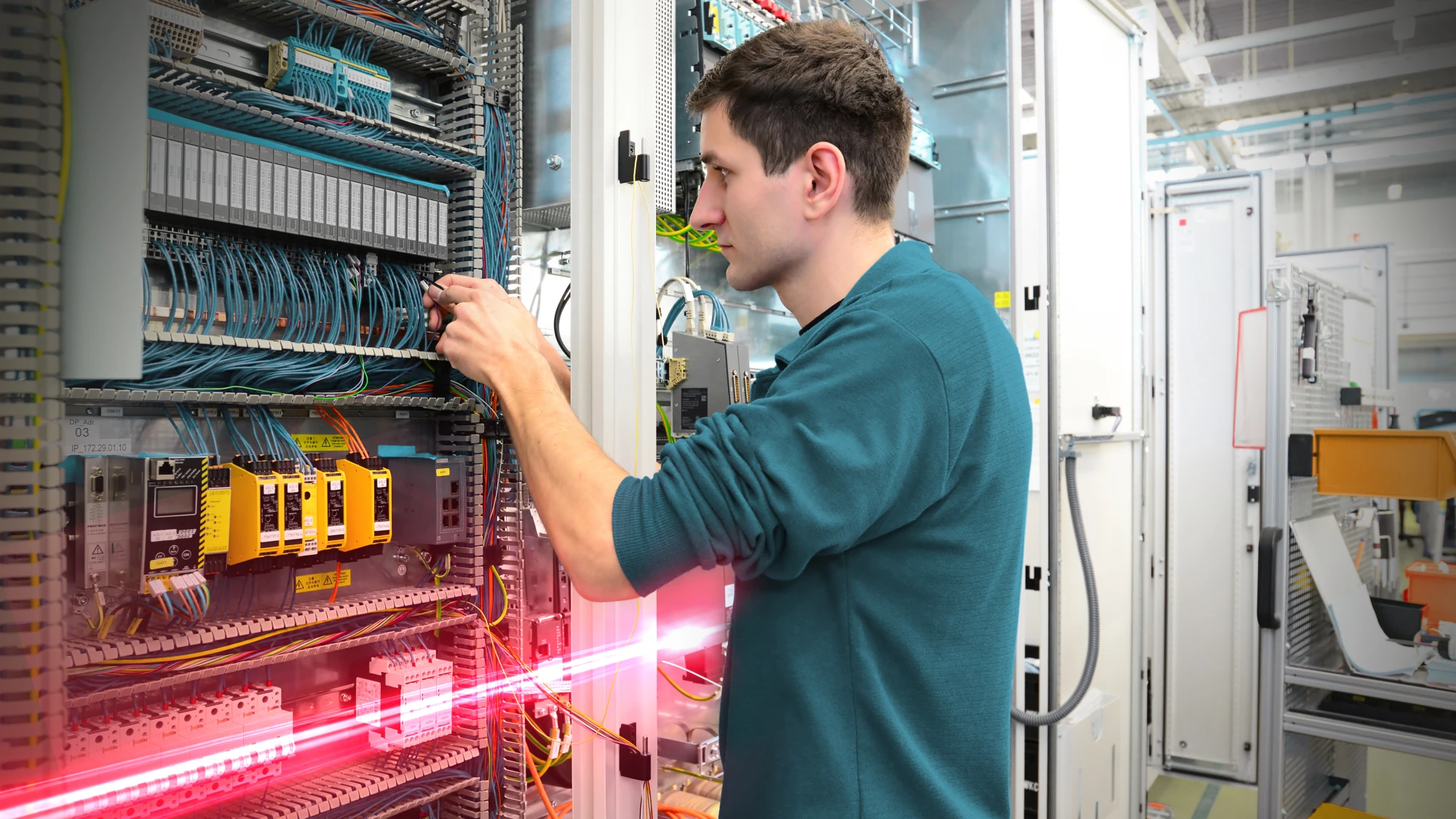 junger Mann vor einem Schaltschrank